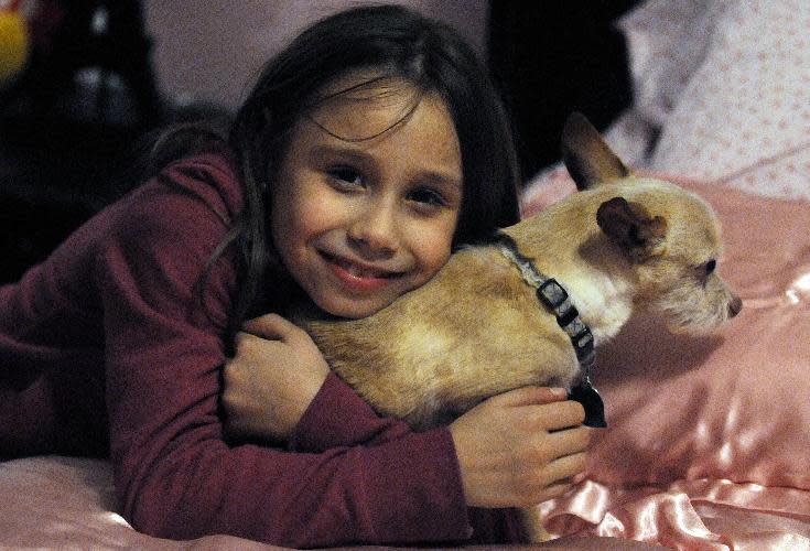 In this photo from Feb. 23, 2014, Alla Bundy relaxes on her new bed with Tucker in her new home in Montgomery, Ala. David Bundy and three of their newly adopted children, Karina, Max and Alla, arrived home from the Ukraine on Sunday, while Lisa Bundy remains in Ukraine until the adoption of their daughter Nastia is finalized. (AP Photo/Montgomery Advertiser, Amanda Sowards) NO SALES.