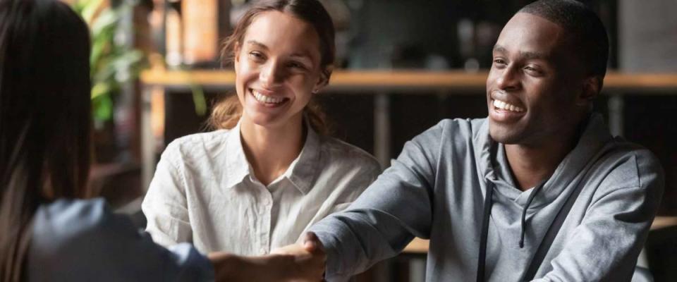 Happy young interracial couple shake hand of bank manager broker