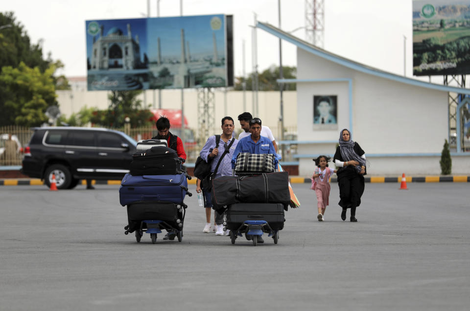 Passengers walk to the departures terminal of Hamid Karzai International Airport in Kabul, Afghanistan, Saturday, Aug. 14, 2021. As a Taliban offensive encircles the Afghan capital, there's increasingly only one way out for those fleeing the war, and only one way in for U.S. troops sent to protect American diplomats still on the ground: the airport. (AP Photo/Rahmat Gul)