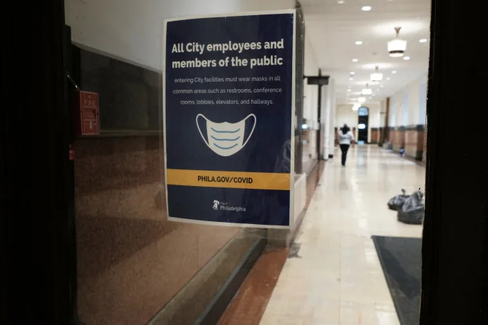 A sign on a door in Philadelphia reads: All city employees and members of the public entering city facilities must wear a mask in all common areas.