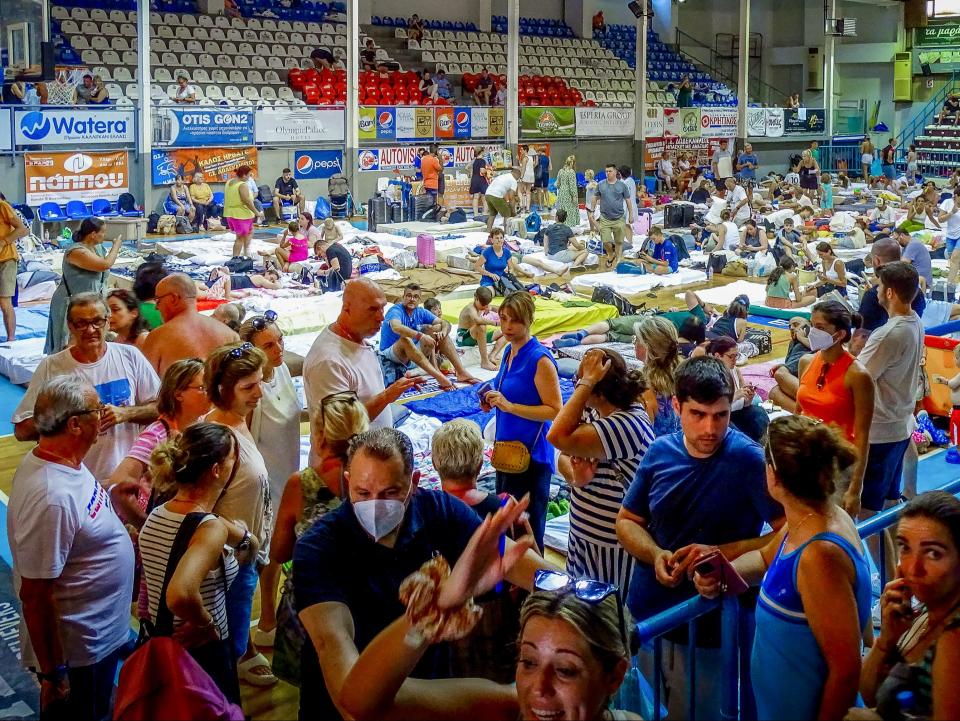 Evacuees sit inside a stadium following their evacuation during a forest fire on the island of Rhodes (AP)