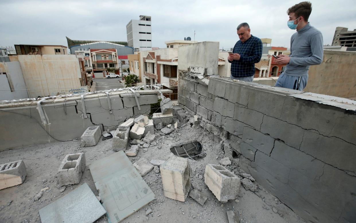 People stand next to a roof damaged after a rocket attack on U.S.-led forces in and near Erbil International Airport last night, in Erbil, Iraq February 16, 2021. REUTERS/Azad Lashkari - Azad Lashkari/Reuters 