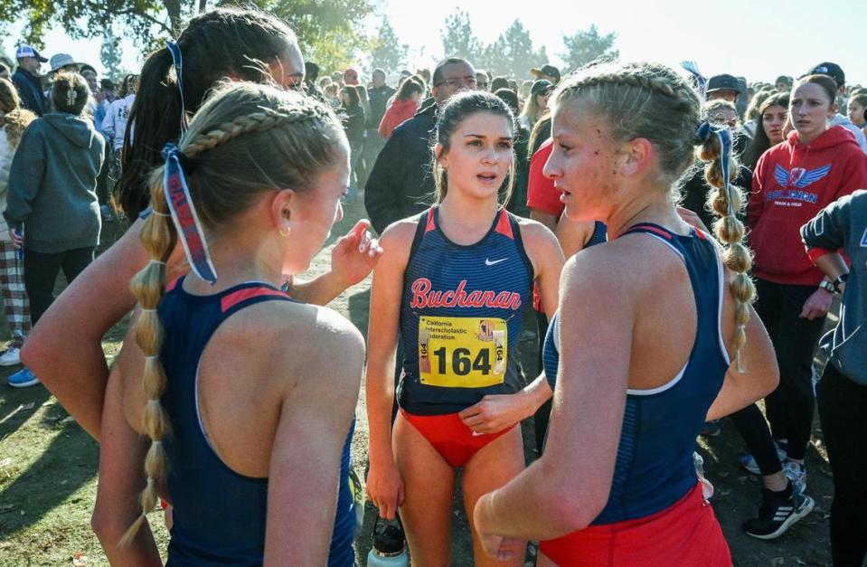 Buchanan girls cross country runners, including Kynzlee Buckley, center, and Tayler Torosian, right, gather after finishing the girls Division I state cross country championships at Woodward Park in Fresno on Saturday, Nov. 25, 2023.