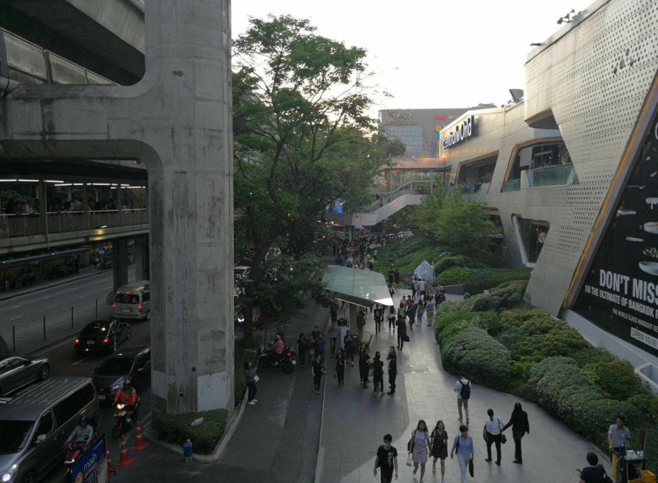 In this photo provided by Zhuang Jing, visitors exit the Central World mall complex, Wednesday, April 10, 2019, in downtown Bangkok, Thailand. A fire has broken out at a major mall complex in Thailand's capital, with initial reports from Thai emergency services saying the fire has caused fatalities. (Zhuang Jing via AP)