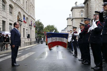 French President Francois Hollande (L) listens to the national anthem during a ceremony to mark the 70th anniversary of the Liberation of Paris from Nazi occupation, at the Police headquarters in Paris, August 25, 2014. REUTERS/Yoan Valat/Pool