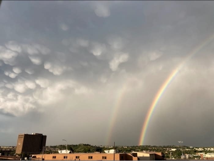 Double rainbow over a cityscape with cloudy skies