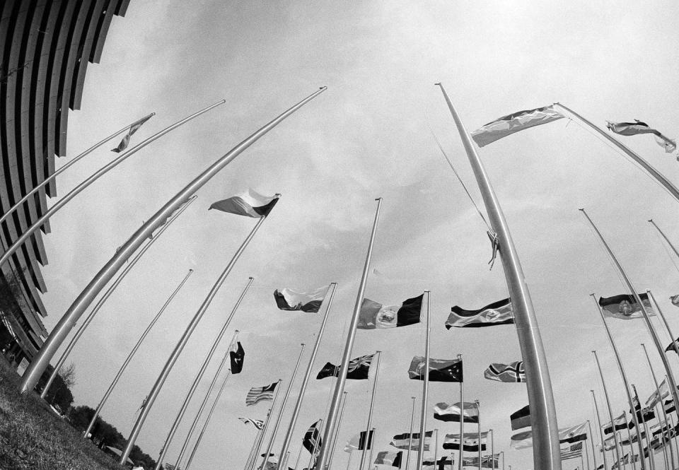 Flagless poles stand in the foreground. Poles with country flags on them stand in the background.