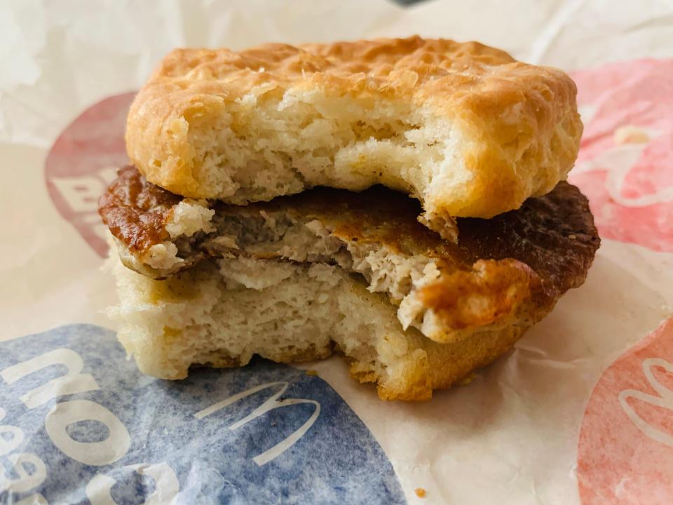 McDonald's sausage biscuit with bite taken out of it on white wrapper