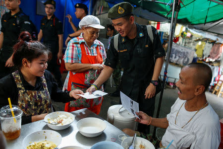 A student from the military's territorial defence program offers brochures during a military campaign to tell people to vote in an August referendum on a new constitution in Bangkok, Thailand, April 19, 2016. REUTERS/Athit Perawongmetha