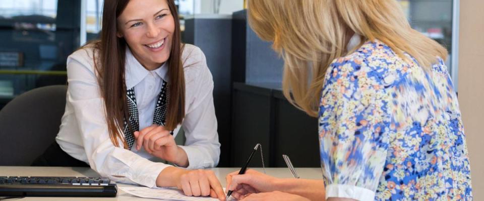 Two happy business women talking and signing credit or insurance