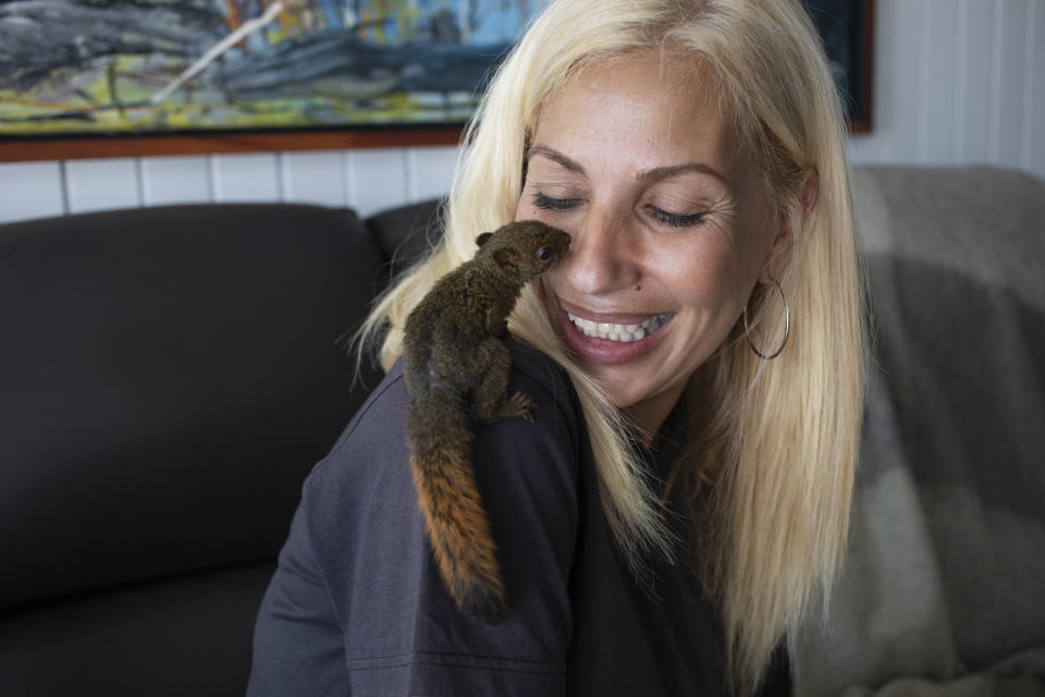 Carmen Borges, a reiki therapist, smiles at a baby squirrel perched on her shoulder in her apartment in Caracas, Venezuela, Friday, Sept 11, 2020. Borges converted her small apartment, where she lives with her husband and two of her three daughters, into a shelter for a dray of baby squirrels who were rescued from the middle of a street by a neighbor. (AP Photo/Ariana Cubillos)