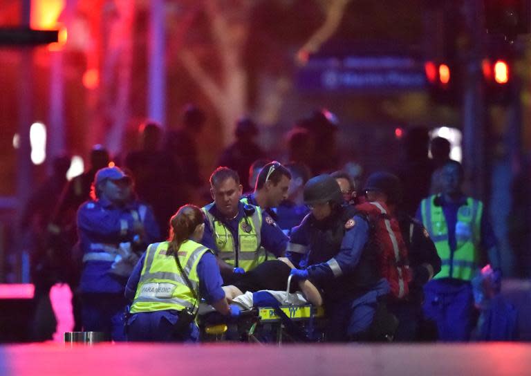 An injured hostage is carried out of a cafe in the central business district of Sydney on December 16, 2014