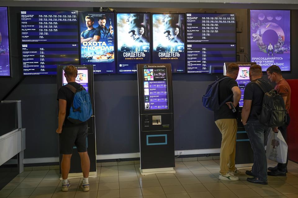 People stand at ticket machines in a cinema lobby inside a shopping mall in Moscow, Russia, Thursday, Aug. 17, 2023. "The Witness," a state-sponsored drama that premiered in Russia on Aug. 17, is the first feature film about Russia's military campaign in Ukraine to hit the movie theaters nationwide. It depicts Ukrainian troops as violent neo-Nazis who torture and kill their own people. (AP Photo/Alexander Zemlianichenko)