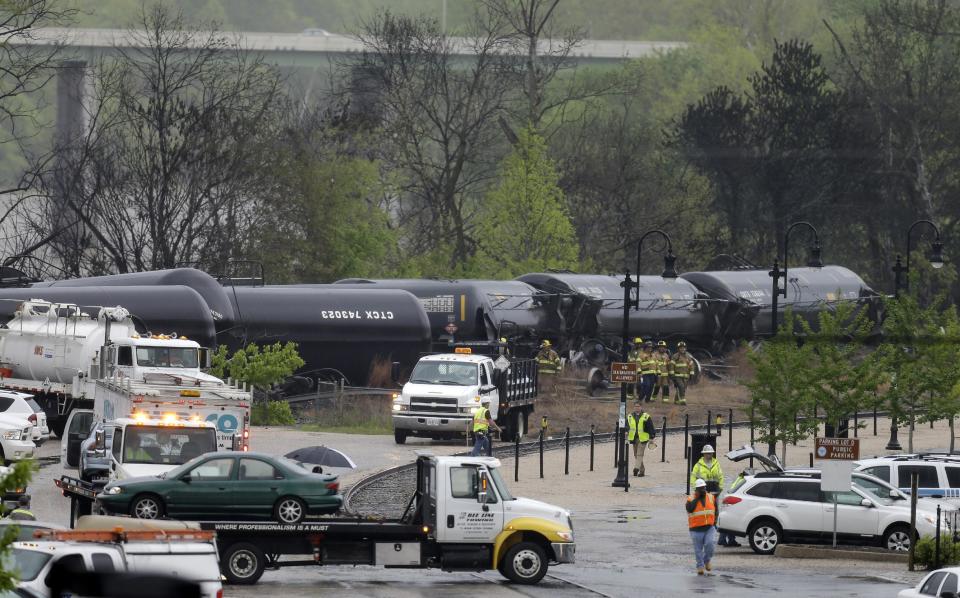 Firefighters and rescue workers work along the tracks where several CSX tanker cars carrying crude oil derailed and caught fire along the James River near downtown in Lynchburg, Va.., Wednesday, April 30, 2014. (AP Photo/Steve Helber)