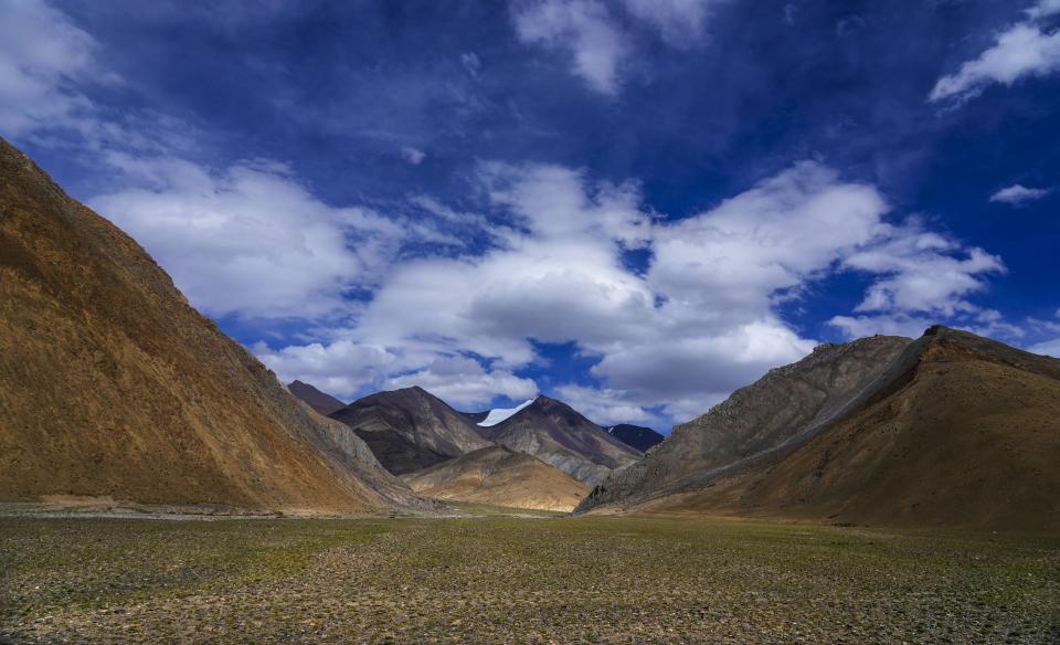 A view of a glacier on mountaintop and grazing land near the remote Kharnak village in the cold desert region of Ladakh, India, Saturday, Sept. 17, 2022. Ladakh’s thousands of glaciers, which help give the rugged region its title as one of the water towers of the world, are receding at an alarming rate, threatening the water supply of millions of people. (AP Photo/Mukhtar Khan)