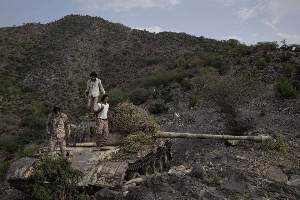 FILE - In this Aug. 5, 2019 file photo, fighters from a militia known as the Security Belt, funded and armed by the United Arab Emirates, stand on a tank camouflaged with brush at the Gabhet Hajr frontline with Houthi rebels, in Yemen's Dhale province. Fighting between their allies in southern Yemen has opened a gaping wound in the Saudi Arabia and the United Arab Emirates’ coalition fighting the country’s rebels. If they can’t fix it, it threatens to further fragment the country into smaller warring pieces. (AP Photo/Nariman El-Mofty, File)