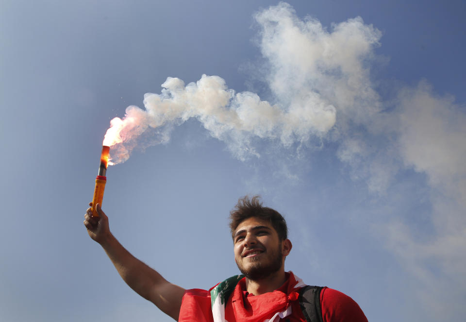 A student protester holds a smoke flare during a protest against the government in front of the education ministry in Beirut, Lebanon, Friday, Nov. 8, 2019. Lebanese protesters are rallying outside state institutions and ministries to keep up the pressure on officials to form a new government to deal with the country's economic crisis. (AP Photo/Hussein Malla)