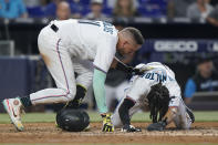 Miami Marlins' Miguel Rojas, left, checks on Billy Hamilton when Hamilton stayed down after scoring against the Pittsburgh Pirates during the fifth inning of a baseball game, Thursday, July 14, 2022, in Miami. (AP Photo/Wilfredo Lee)