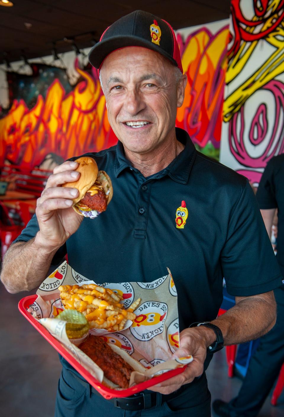 Bob Quinlan, co-owner of Dave's Hot Chicken, holds one of the restaurant's most popular items, a slider, at its newest location at 341 Cochituate Road in Framingham, July 26, 2023. Each piece is topped with Dave’s signature mix of spices, ranging from no spice to “reaper.”