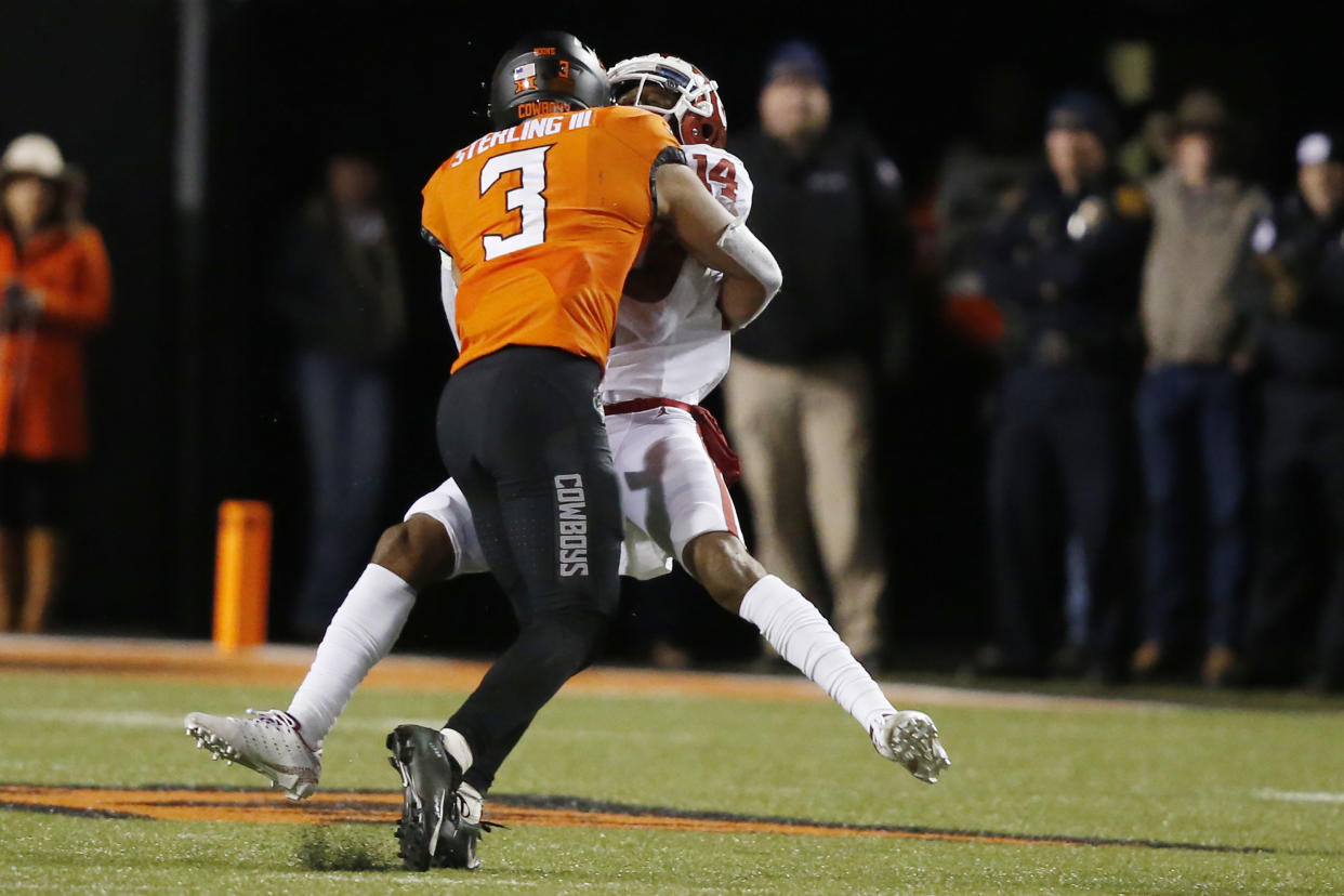 Oklahoma wide receiver Charleston Rambo (14) is hit by Oklahoma State safety Tre Sterling (3) in the second half of an NCAA college football game in Stillwater, Okla., Saturday, Nov. 30, 2019. Sterling was ejected for targeting on the play. (AP Photo/Sue Ogrocki)