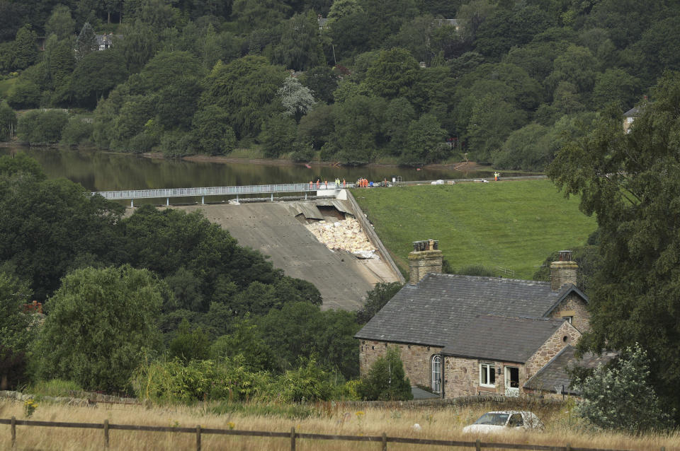 A view of the damaged Toddbrook Reservoir near the village of Whaley Bridge,in Derbyshire, England, Saturday, Aug. 3, 2019. Emergency workers are racing to lower water levels behind a damaged dam in northwest England as forecasters warn more bad weather is on the way. Pumps have reduced the water level in Toddbrook Reservoir by half a meter (20 inches) since Thursday, but authorities warn that pressure on the 180-year-old dam remains severe. (Yui Mok/PA via AP)