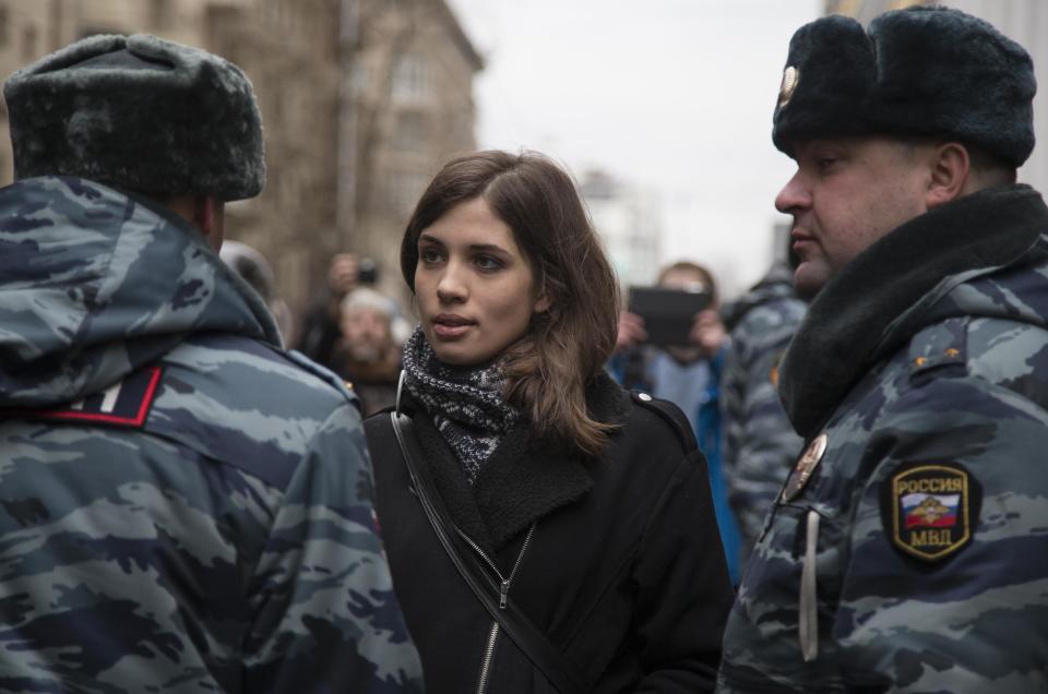 Member of the Pussy Riot punk group, Nadezhda Tolokonnikova, center, speaks to a police officer outside Zamoskvoretsky District Court in Moscow, Russia, Monday, Feb. 24, 2014, where hearings started against opposition activists detained on May 6, 2012 during the rally at Bolotnaya Square. A Moscow judge on Friday, Feb. 21, 2014, convicted eight anti-government protesters of rioting during a 2012 protest against Vladimir Putin, following a trial seen as part of the Kremlin's efforts to stifle dissent. (AP Photo/Alexander Zemlianichenko)