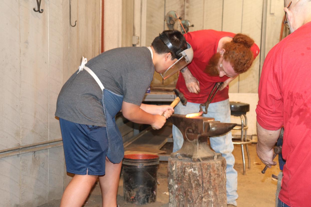 A boy hammers a piece of metal at a blacksmith activity at Dollywood