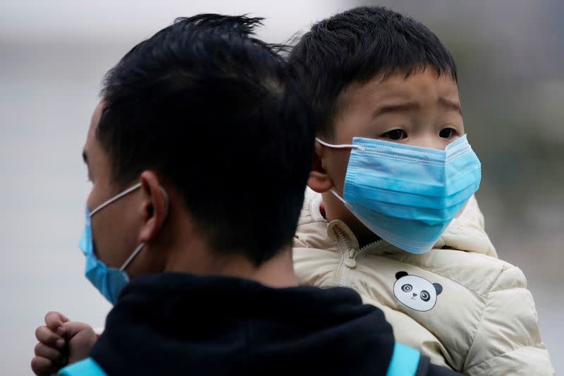 Passengers wearing masks walk outside the Shanghai railway station in Shanghai