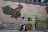 A woman wearing a face mask to help protect herself from the coronavirus walks by a map showing Evergrande development projects in China, at an Evergrande city plaza in Beijing, Tuesday, Sept. 21, 2021. Global investors are watching nervously as the Evergrande Group, one of China's biggest real estate developers, struggles to avoid defaulting on tens of billions of dollars of debt, fueling fears of possible wider shock waves for the Chinese financial system. (AP Photo/Andy Wong)