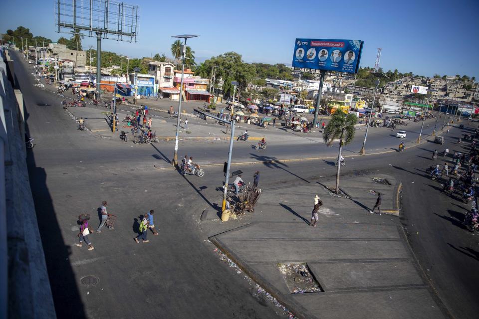 People walk in a street left empty by a nationwide strike demanding the resignation of Haitian President Jovenel Moise in Port-au-Prince, Haiti, Monday, Feb. 1, 2021. (AP Photo/Dieu Nalio Chery)