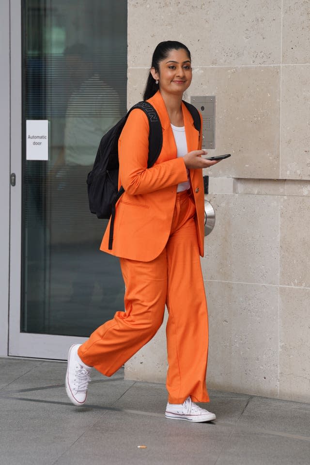 A woman wearing an orange trouser suit and a white T-shirt