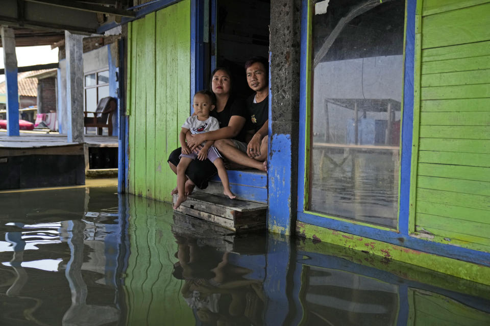 Jaka Sadewa, right, his wife Sri Wahyuni and son Bima pose for a photo in Timbulsloko, Central Java, Indonesia, Sunday, July 31, 2022. "I'm worried that every year the water will get higher. But we don't have any resources," she says. "If we had resources, we would move out." (AP Photo/Dita Alangkara)