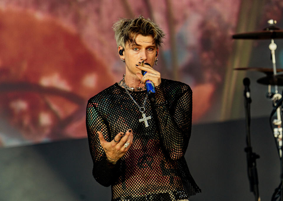 MGK in a mesh top performing onstage with a microphone