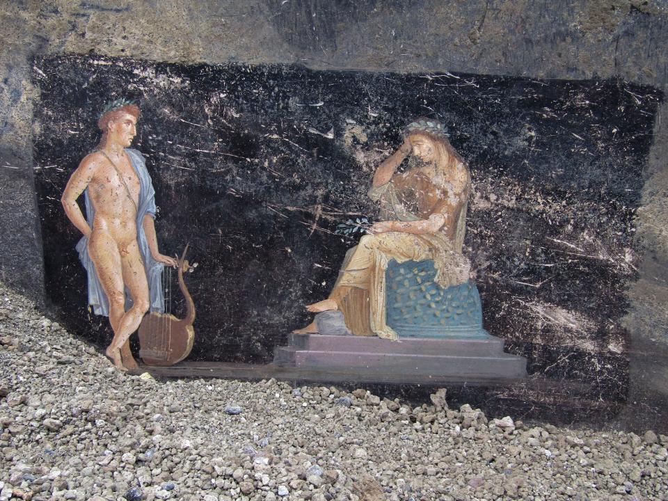 A fresco on a black wall showing Cassandra, right, a cursed prophetess, and Apollo, God of oracles and knowledge