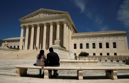 FILE PHOTO: A couple sit in front of the U.S. Supreme Court in Washington, U.S. on May 16, 2016. REUTERS/Kevin Lamarque/File Photo