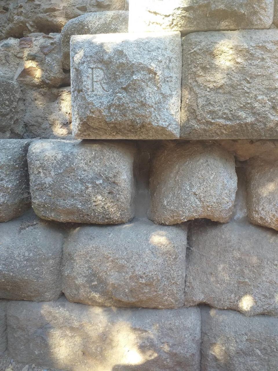 La letra R de la piedra significa que está restaurada. El resto, es el muro original del teatro romano.