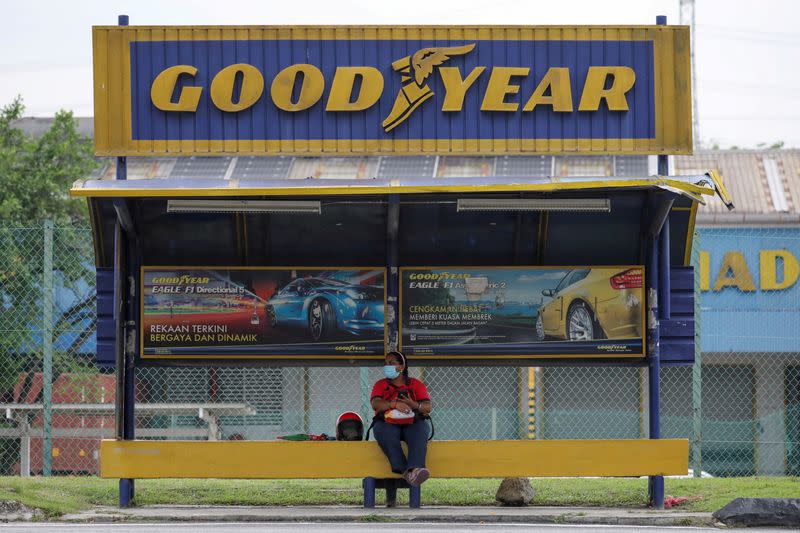 FILE PHOTO: A woman sits at a bus stop outside Goodyear factory in Shah Alam