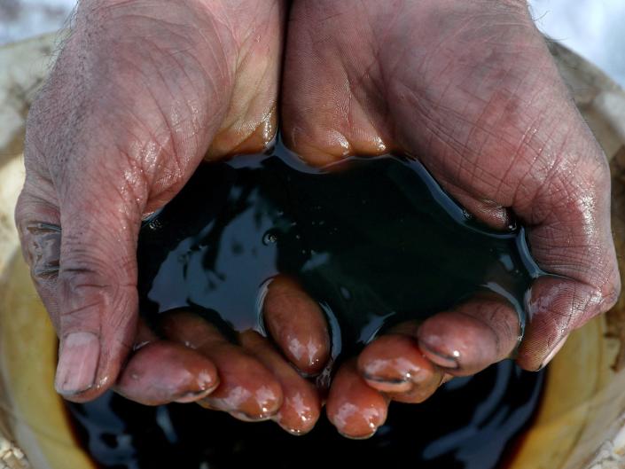par de manos ahuecadas sosteniendo petróleo crudo