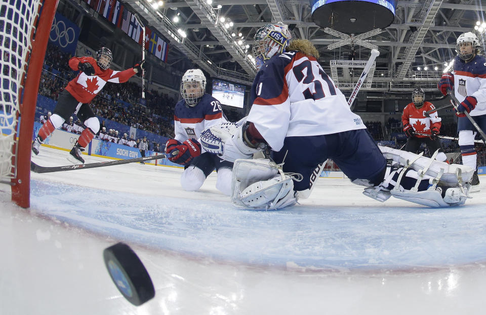 Goalkeeper Jessie Vetter and Kendall Coyne (26) of the United States look back at the puck as Meghan Agosta-Marciano, left, of Canada celebrates her goal during women's ice hockey game at the 2014 Winter Olympics, Wednesday, Feb. 12, 2014, in Sochi, Russia. Canada defeated the United States 3-2.