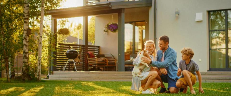 Smiling Father, Mother and Son Pet and Play with Smooth Fox Terrier Retriever Dog. Sun Shines on Idyllic Happy Family