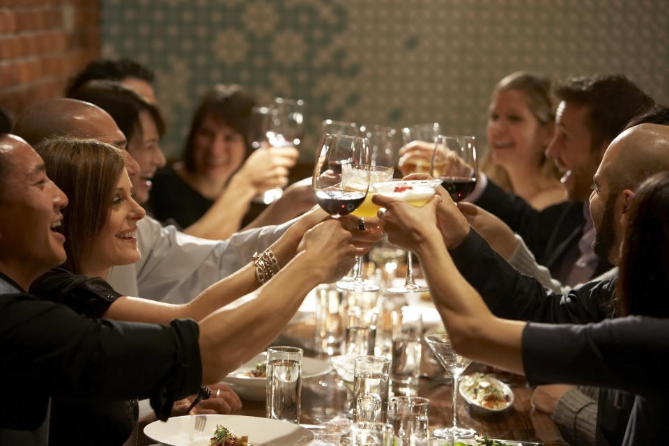 People sitting at a dinner table raise their glasses.