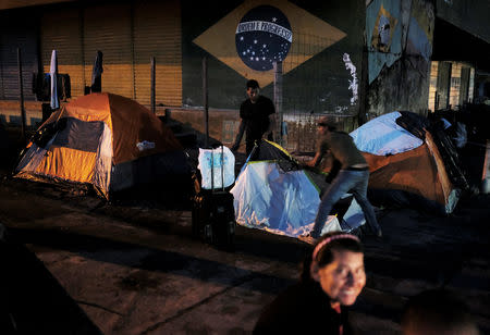 FILE PHOTO: Venezuelan men erect their tent to sleep along the street as they wait to show their passports or identity cards next day at the Pacaraima border control, Roraima state, Brazil August 8, 2018. Picture taken August 8, 2018. REUTERS/Nacho Doce