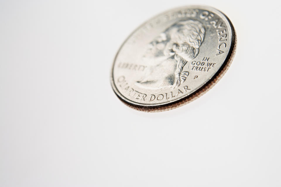 A close-up of a quarter tilted on a white surface, showing part of George Washington's profile