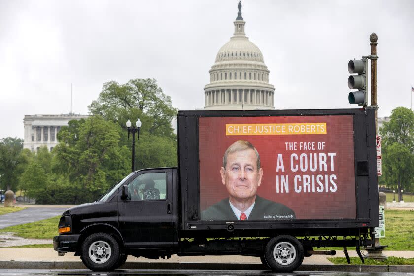 A mobile billboard showing Justice Roberts and a sign "The face of the court in crisis" drives near the U.S. Capitol