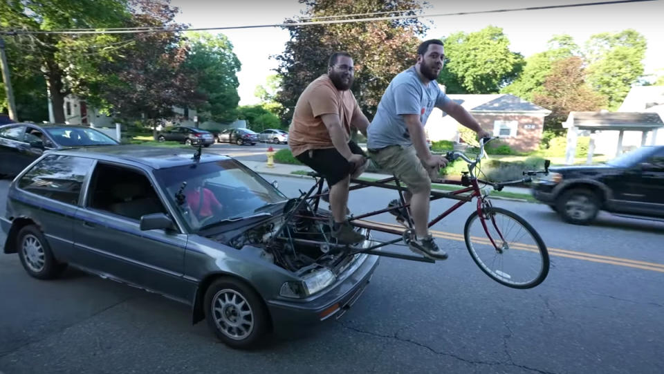 Two men driving a bicycle-powered car to McDonald's.