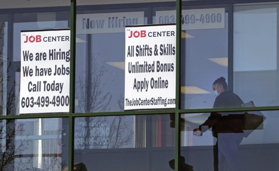 FILE - In this March 2, 2021, file photo, a woman, wearing a protective mask due to the coronavirus, walks past the signs of an employment agency, in Manchester, N.H. A new report finds that Latinas have left the workforce at rates higher than any other demographic and also have had some of the highest unemployment rates throughout the pandemic. (AP Photo/Charles Krupa, File)