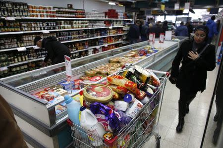 A woman walks near a shopping trolley full of products in a supermarket in Jerusalem January 6, 2015. REUTERS/Ronen Zvulun