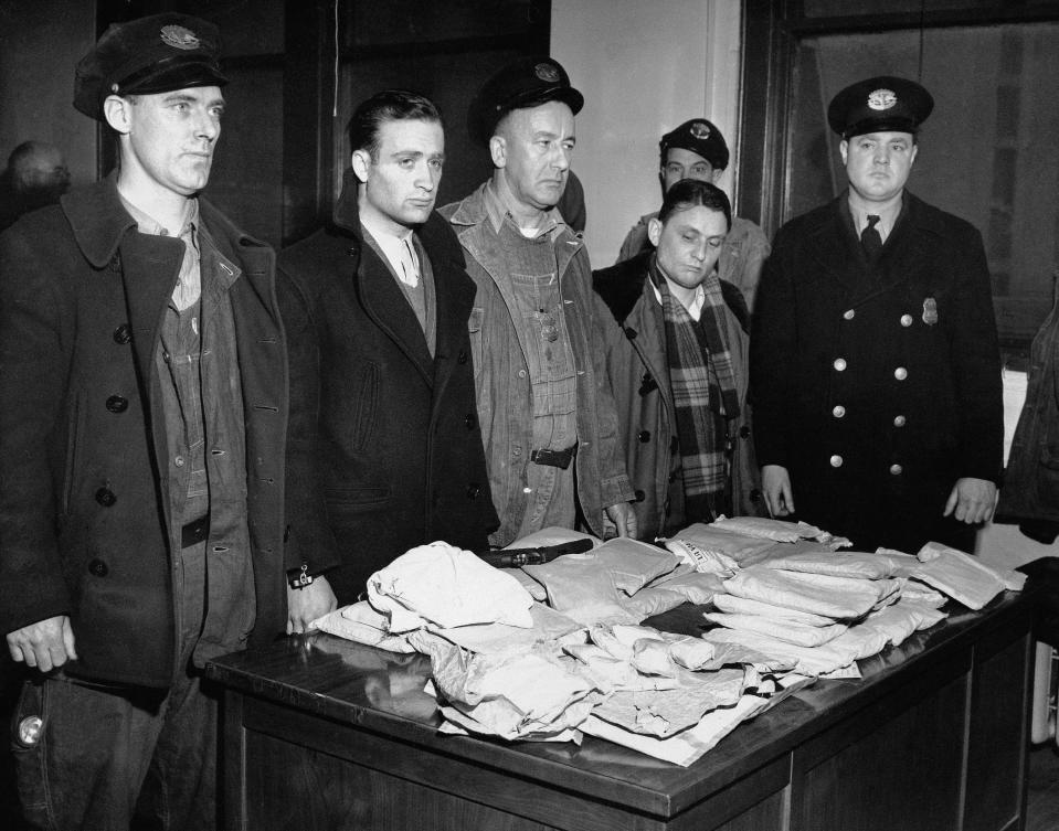 FILE - In this March 17, 1947 file photo, about 459 ounces of pure heroin valued at over one million dollars in the black market lies on table in Customs Enforcement Bureau in New York following seizure aboard the French freighter Saint Tropez after its arrival in New York City from Marseilles. Cesar Negro, Marseilles seaman, second from left, was arrested on charges of smuggling narcotics and Rene Bruchard, second from right, the ship's linen keeper, is being held for questioning. Port Patrol Officers Michael F. Munro, left; Arthur H. Cumming, center, and Lawrence F. Murray, right, are credited with discovering the heroin during a routine check of the seamen. (AP Photo)