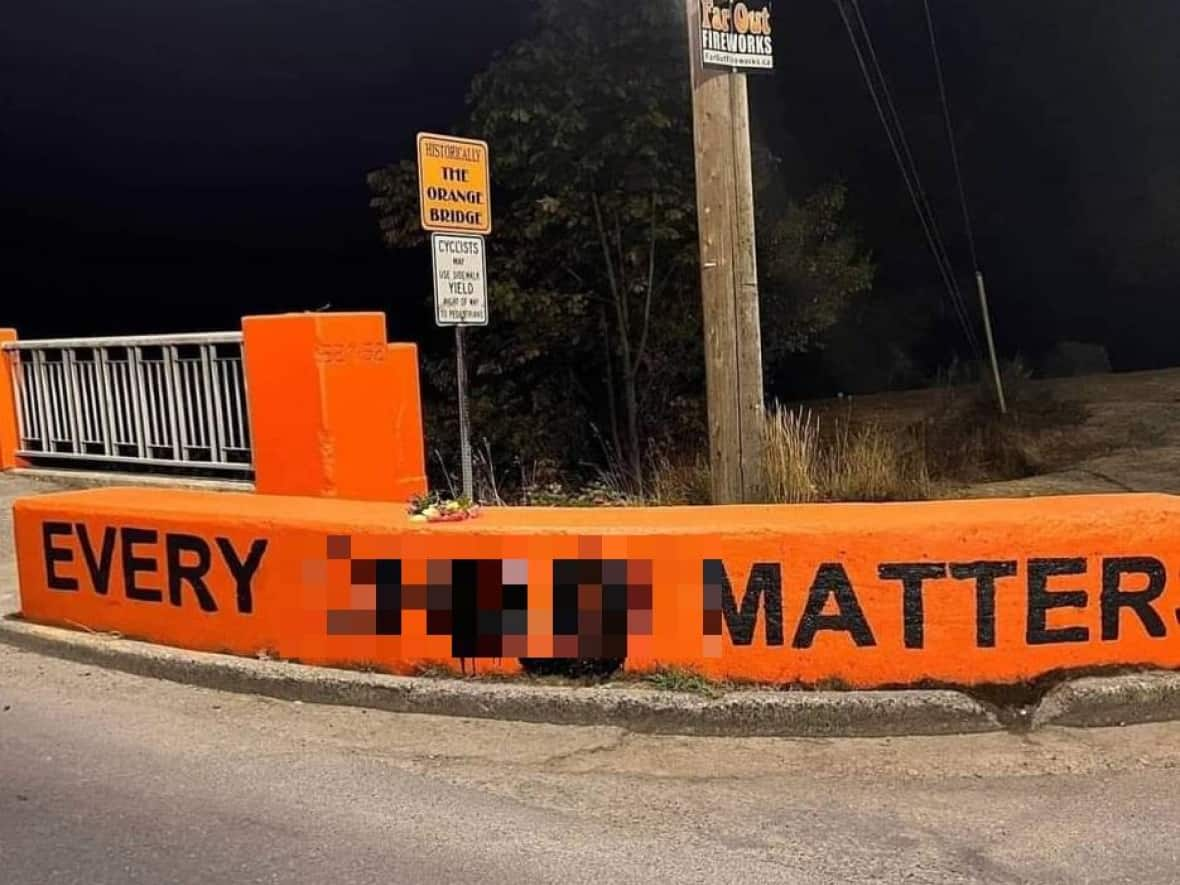 A barrier at Riverbend Bridge, which leads to the former residential school in Port Alberni, B.C., was vandalized with an anti-Indigenous slur on Friday night, according to RCMP. (Port Alberni RCMP - image credit)