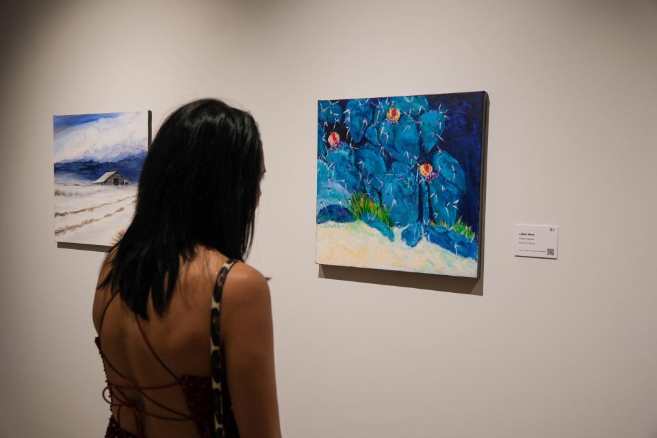 A patron looks over one of the over 100 paintings at the 20x20 Art Exhibition and Silent Auction at the Amarillo Museum of Art on the campus of Amarillo College.